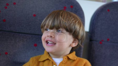 Téléchargez les photos : Un enfant heureux petit garçon passager sur le siège du train souriant et riant pendant le voyage - en image libre de droit
