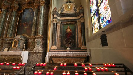 Foto de Friburgo, Suiza Circa Marzo 2022 - Pintura de Jesucristo dentro de la Catedral de San Nicolás, Refugio espiritual dentro de un pilar católico con velas encendidas para el culto - Imagen libre de derechos
