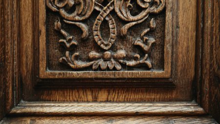 Photo for Timeless Craftsmanship - Engraved Adornments on Antique Wooden Door of Traditional Building - Royalty Free Image