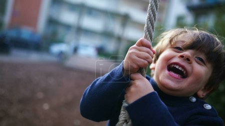 Foto de El niño sostiene apretado y deslizándose hasta el final de la cuerda de alambre en el parque público, el joven se divierte en un momento nostálgico de la niñez, primer plano se desliza en el alambre del parque - Imagen libre de derechos