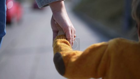 Foto de Madre e hijo tomados de la mano caminando al aire libre - Imagen libre de derechos