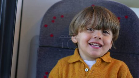 Foto de Un niño pasajero feliz niño en el asiento del tren sonriendo y riendo mientras viaja - Imagen libre de derechos