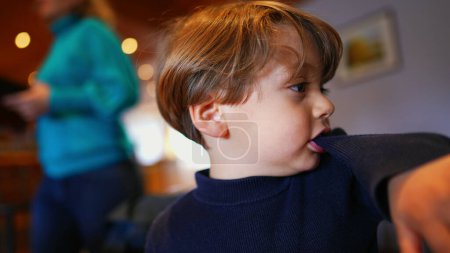 Téléchargez les photos : Morsures d'ennui, Petit garçon tirant la manche avec les dents, ralenti au restaurant - en image libre de droit