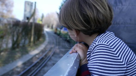 Photo for Child riding miniature train at Swiss vapeur observing railroad view, small boy leaning from wagon in motion - Royalty Free Image