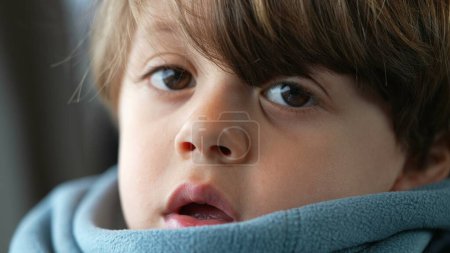 Téléchargez les photos : Portrait d'un petit garçon caucasien orné d'une écharpe, profondément imprégné de pensée, exsudant un profond sens de réflexion et d'introspection - en image libre de droit