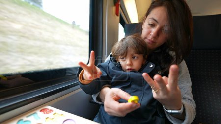 Foto de Madre enseñando a su hijo a contar mientras viaja en tren. Padres atentos educando a su hijo en casa, concepto de educación infantil - Imagen libre de derechos
