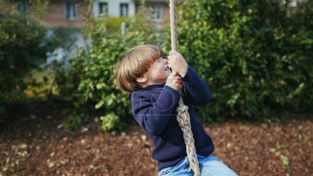 Photo for Happy child rope sliding at park between two trees. Small boy feeling excitement during fall autumn day - Royalty Free Image