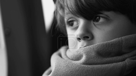 Foto de Cara monocromática de primer plano de un niño pensativo con bufanda mirando hacia fuera en la reflexión mental profunda, niño reflexivo en blanco y negro - Imagen libre de derechos
