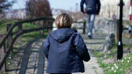 Foto de Niño con chaqueta corriendo alegremente en el camino al aire libre, participando en actividades lúdicas durante la temporada de otoño - Imagen libre de derechos