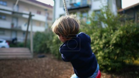 Photo for Joyful Small Boy Sliding Down Wire Rope Between Trees, Close-Up. Public playground park of child in nostalgic scene depiction - Royalty Free Image