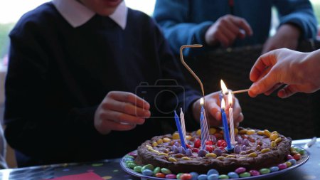 Téléchargez les photos : Jeune garçon célébrant son anniversaire devant son gâteau au chocolat avec des bougies. Célébration enfant 7 ans - en image libre de droit