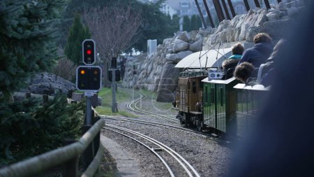 Foto de Personas montando un tren en miniatura en el vapor suizo visto desde la perspectiva de los pasajeros en el movimiento de las vías del ferrocarril - Imagen libre de derechos