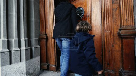 Téléchargez les photos : Mère et enfant tenant la main marchant dans le temple religieux atteignant la poignée de porte et s'ouvrant à la porte traditionnelle en bois - en image libre de droit