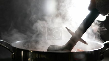 Foto de Humo que sale de cocinar la sartén de alimentos, revolviendo y preparando la comida - Imagen libre de derechos