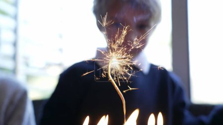 Foto de Sparkler ardiendo en la celebración de la torta de cumpleaños con el niño en el fondo celebrando durante el día de fiesta - Imagen libre de derechos