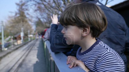 Téléchargez les photos : Joyeux petit garçon penché du wagon, observant la vue du chemin de fer en train miniature à Swiss Vapeur - en image libre de droit