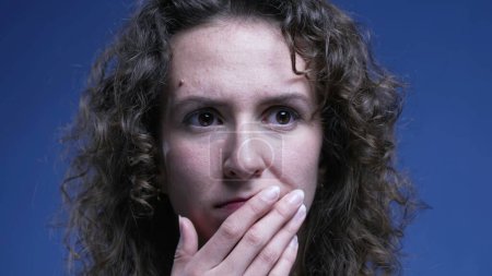 Photo for Anxious woman close-up face covering mouth with hand with preoccupied pensive expression, 20s female person struggling with mental angst - Royalty Free Image