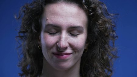 Foto de Primer plano de la cara de la mujer cerrando los ojos sintiendo alivio sonriendo después de realizar la tarea. Emoción libre de estrés de la persona de 20 años sintiéndose feliz y relajado - Imagen libre de derechos
