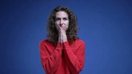 Photo for Indecisive young woman struggles with decision making looking sideway trying to decide between two options. 20s person on blue backdrop - Royalty Free Image
