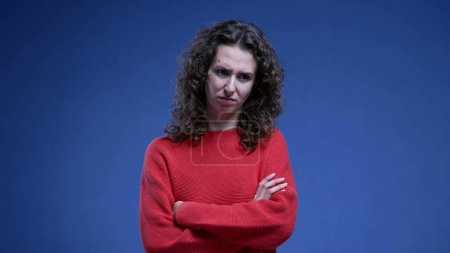 Photo for Woman feeling disgust and apprehension by crossing arms while feeling anxious and fearful standing on blue background, 20s female person in distraught stress emotion - Royalty Free Image