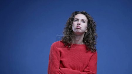 Téléchargez les photos : Femme se sentant ennuyée soupirant profondément avec les bras croisés regardant vers le haut et roulant les yeux dans l'ennui debout sur fond bleu - en image libre de droit