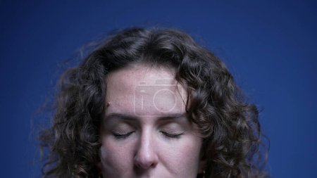 Photo for Young woman close-up eyes in meditation and contemplation on blue backdrop. Detail face of person introspecting and opening eyes feeling relaxed - Royalty Free Image