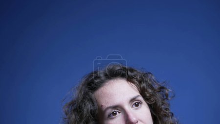Photo for Top of young thoughtful woman opening eyes upwards thinking and problem-solving with blue backdrop good to animate bubble idea imagination - Royalty Free Image