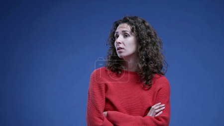 Téléchargez les photos : Femme se sentant ennuyée soupirant profondément avec les bras croisés regardant vers le haut et roulant les yeux dans l'ennui debout sur fond bleu - en image libre de droit