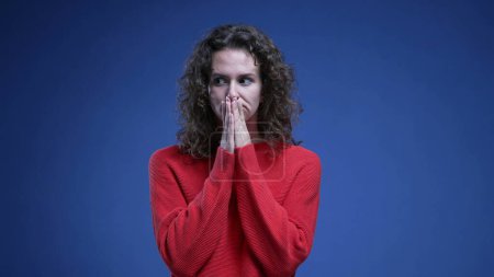 Photo for Indecisive young woman struggles with decision making looking sideway trying to decide between two options. 20s person on blue backdrop - Royalty Free Image
