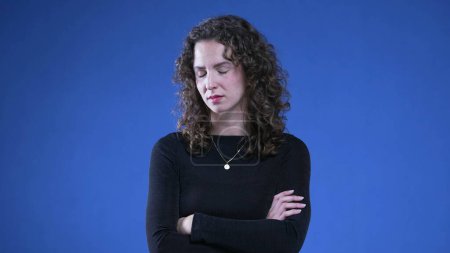 Photo for Upset woman with arms crossed looking at camera with angry expression, standing on blue background. Female person in 20s with negative body language - Royalty Free Image