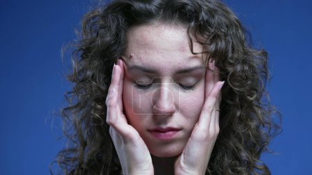 Téléchargez les photos : Stressé écrasé jeune femme essayant d'apaiser sa nervosité en mettant les mains sur le côté des tempes de la tête se sentant frustrationn et anxiété - en image libre de droit