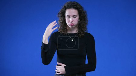 Foto de Mujer sintiendo el calor saludando mano a cara de pie sobre fondo azul - Imagen libre de derechos
