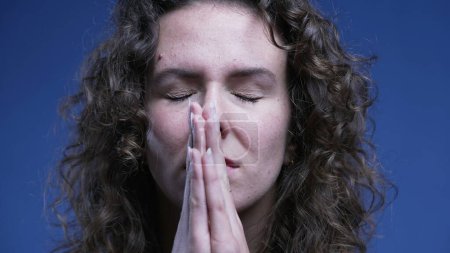 Photo for Woman praying to God with hand clenched together looking up with HOPE and FAITH close-up face - Royalty Free Image