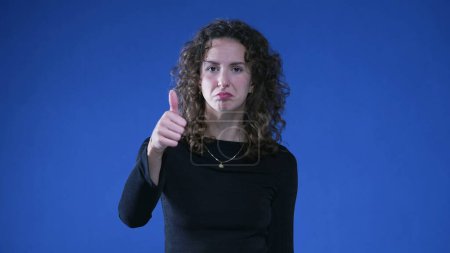 Photo for Happy woman showing approval with thumb up, looking at camera while standing on blue background. Approved concept - Royalty Free Image