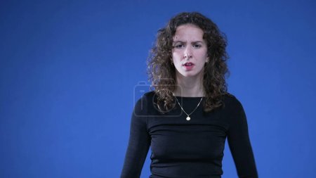 Photo for Shocked woman reacting with perplexity on blue background with hands on hip, surprised annoyed and disbelief - Royalty Free Image