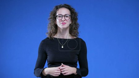 Photo for Portrait of a Happy smart 20s woman wearing reading glasses standing on blue background smiling at camera - Royalty Free Image