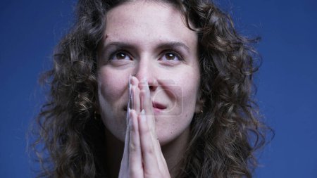 Photo for Woman praying to God with hand clenched together looking up with HOPE and FAITH close-up face - Royalty Free Image