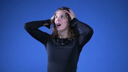 Photo for Anxious apprehensive woman reacting with shock and despair to news by putting arms on top of head and covering mouth in disbelief and surprise - Royalty Free Image