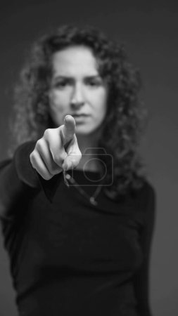 Téléchargez les photos : Femme accusant spectateur en pointant du doigt vers la caméra en noir et blanc monochromatique dramatique. Personne qui vous dit avec la main - en image libre de droit
