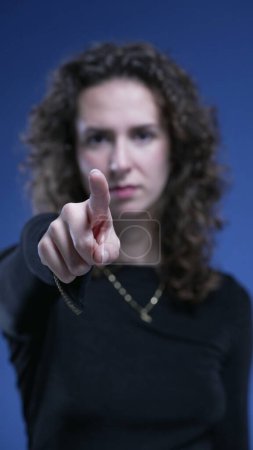 Photo for Close-up woman waving FINGER saying NO to camera by rejecting OFFER. stern serious body language of 20s person waves hand in negation on blue backdrop - Royalty Free Image