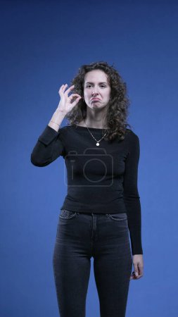Photo for Woman showing signs of approval by giving THUMBS UP and giving OK sign with hand, applauds to camera engaging and supporting cause looking directly at camera - Royalty Free Image