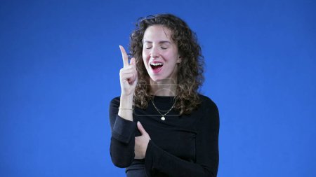 Photo for Thoughtful Woman with Sudden Insight, Eureka Epiphany on Blue background raising hand and finger in the air feeling enlightened - Royalty Free Image