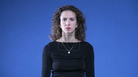 Photo for Woman frowning reaction to camera on blue background. Person listening to strange anecdote - Royalty Free Image