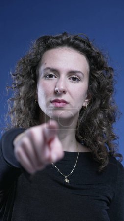 Foto de Mujer señalar con el dedo a la cámara diciendo USTED con el lenguaje corporal, telón de fondo azul - Imagen libre de derechos