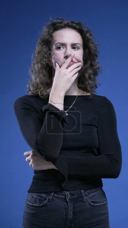 Photo for Thoughtful woman thinking deeply about decision with hand on chin in blue background. Caucasian female person in 20s pensive emotion, pondering dilemma - Royalty Free Image