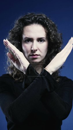 Photo for Close-Up of Stern Woman Waving Finger Saying No on blue backdrop - Royalty Free Image