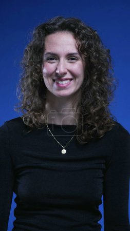 Photo for Portrait of joyful female 20s person looking at camera on blue backdrop smiling. Curly hair woman - Royalty Free Image