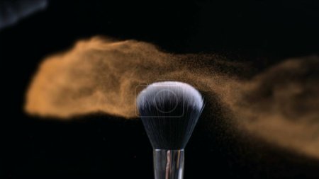 Photo for Orange Makeup brush on dark background and small particles of cosmetics, super slow motion, 1000 fps, detail closeup in macro - Royalty Free Image