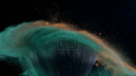 Photo for Macro close-up of cosmetic brush clashing in super slow motion captured with a high speed camera at 1000 fps with orange and green powder flying in the air - Royalty Free Image