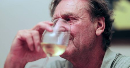 Téléchargez les photos : Homme plus âgé en conversation pendant le dîner, tenant un verre de vin. Interaction franche et occasionnelle des aînés - en image libre de droit
